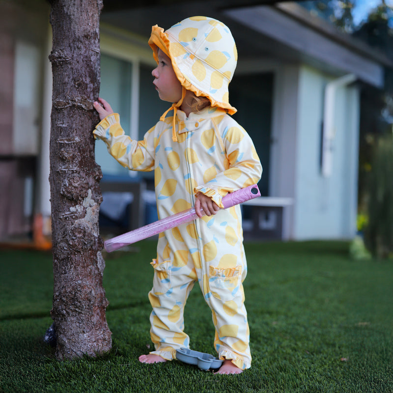 baby girl in grass in sun & swim suit in lemonade stand|lemonade-stand