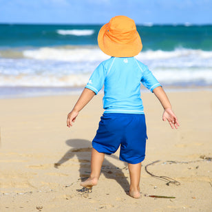 Cute Laughing Baby Boy Wearing Sun Protection Rash Guard Playing With  Bucket And Shovel On Tropical Beach During Family Summer Sea Vacation.  Swimwear And Beach Toys For Kids. Child Digging In Sand.